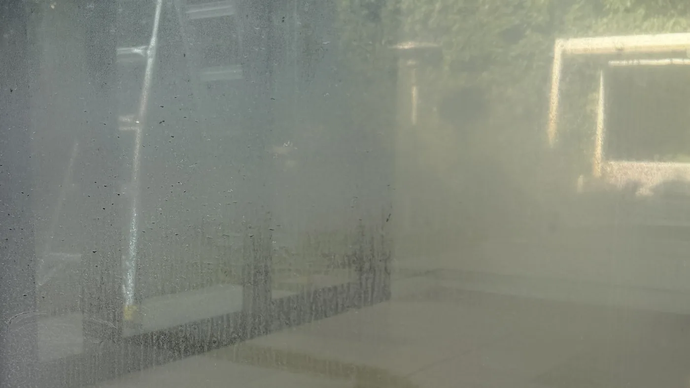 A window covered in white hard-water mineral spots